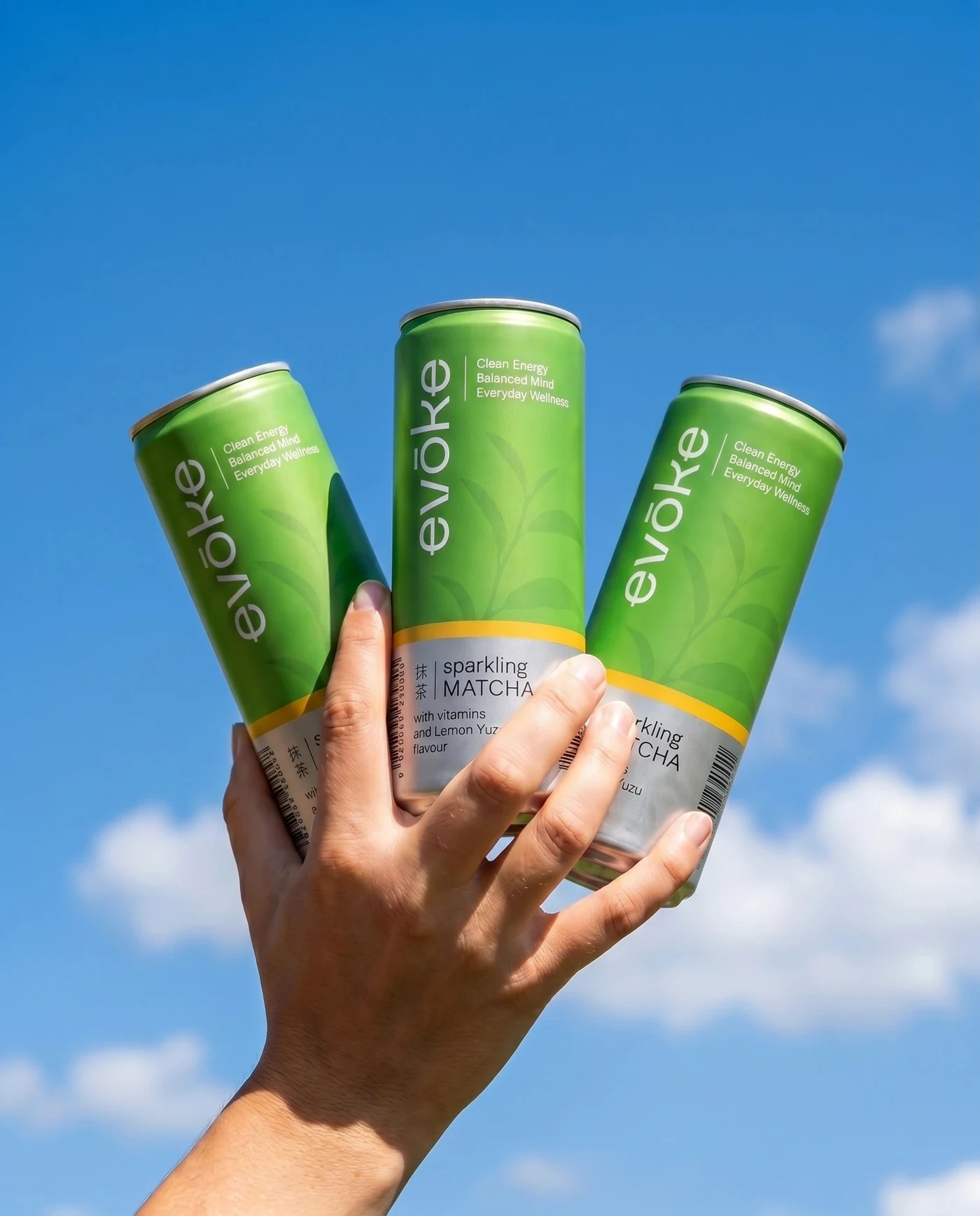 Tři plechovky evōke matcha v ruce pod modrou oblohou